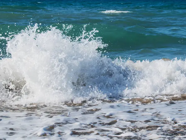 Güçlü deniz dalgaları kıyıya çarpıyor, okyanus spreyi ve köpüğüne yakın plan. Yüksek kalite fotoğraf