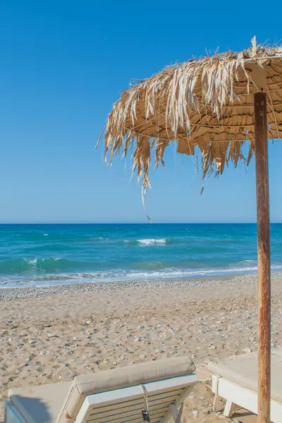 Geleneksel Girit plaj şemsiyesi ve turkuaz denize karşı güneş yatağı. Yüksek kalite fotoğraf