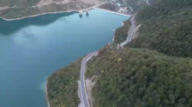 2 Ekim 2022 'de çekilen hava aracı görüntüleri, Gürcistan' ın Tiflis kenti yakınlarındaki Zhinvali Barajı 'nı gösteriyor. Videoda gür orman yamaçları tarafından kucaklanan dolambaçlı bir dağ yolu yer alıyor. Yüksek kalite 4k görüntü