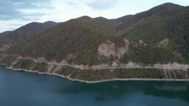2 Ekim 2022 'de, Gürcistan' daki Zhinvali Barajı 'nı çevreleyen yemyeşil ormanları ve manzaralı dağ yolunu gösteren hava aracı videosu çekildi. Yüksek kalite 4k görüntü