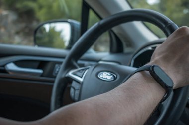 Hanya, Girit, Yunanistan. 23 Mayıs 2025. Ford Fusion 'un direksiyonunda spor takip cihazı olan bir adam. Yüksek kalite fotoğraf