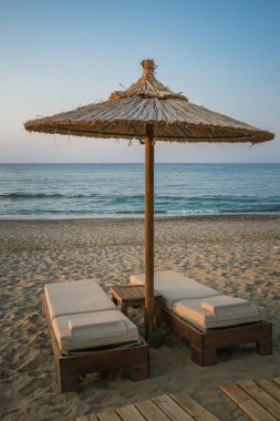 Yunan sahilinde şilteli ve şemsiyeli bir çift tahta güneşlik. Yüksek kalite fotoğraf