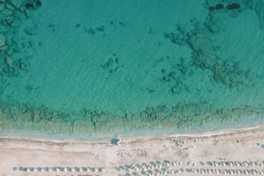 Deniz manzarasının kristal berraklığında su, su altı ferahlığı, beyaz kum ve plaj şemsiyeleri ile insansız hava aracı fotoğrafı - mükemmel bir yaz tatili. Yüksek kalite fotoğraf