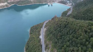 2 Ekim 2022 'de çekilen hava aracı görüntüleri, Gürcistan' ın Tiflis kenti yakınlarındaki Zhinvali Barajı 'nı gösteriyor. Videoda gür orman yamaçları tarafından kucaklanan dolambaçlı bir dağ yolu yer alıyor. Yüksek kalite 4k görüntü