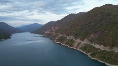 2 Ekim 2022 tarihli gündüz insansız hava aracı görüntüleri, Gürcistan 'daki büyüleyici Zhinvali Barajı' nın canlı yeşil ormanlar ve pitoresk bir dağ yolu tarafından çerçevelendiğini gösteriyor. Yüksek kalite 4k görüntü