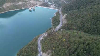 2 Ekim 2022 'de çekilen hava aracı görüntüleri, Gürcistan' ın Tiflis kenti yakınlarındaki Zhinvali Barajı 'nı gösteriyor. Videoda gür orman yamaçları tarafından kucaklanan dolambaçlı bir dağ yolu yer alıyor. Yüksek kalite 4k görüntü