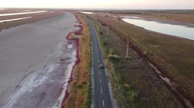 İnsansız hava aracı görüntüsü: Ukrayna 'nın Mariupol bölgesinde Belosarayska Spit' te Bilosaraysky Ornithological Reserve içinde kırmızı yosun ve sulak arazili manzaralı bir araba. 16 Eylül 2021. Yüksek kaliteli FullHD görüntüler