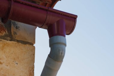 Taştan bir duvarın yakınındaki yağmur suyu drenaj sistemi çatıdan yağış toplamak ve yönlendirmek için tasarlanmış. Yüksek kalite fotoğraf