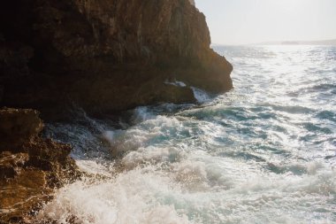 Yazın güneşli bir günde mağaradan denize bakmak. Akdeniz güzellik manzarası. Dalgalar kayalık bir plaja çarpıyor. Yüksek kalite fotoğraf
