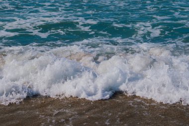 Deniz dalgalarının kumlu sahile yuvarlanıp beyaz köpük oluşturduğu an. Doğal deniz ve tatil geçmişi. Yüksek kalite fotoğraf