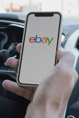 Rethymno, Yunanistan. 16 Temmuz 2025. Mans, Ebay uygulaması açık bir telefonu olan bir arabayı teslim etti. Yüksek kalite fotoğraf