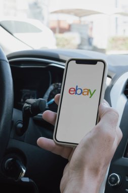 Rethymno, Yunanistan. 16 Temmuz 2025. Mans, Ebay uygulaması açık bir telefonu olan bir arabayı teslim etti. Yüksek kalite fotoğraf