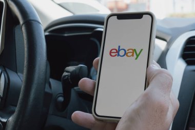 Rethymno, Yunanistan. 16 Temmuz 2025. Mans, Ebay uygulaması açık bir telefonu olan bir arabayı teslim etti. Yüksek kalite fotoğraf