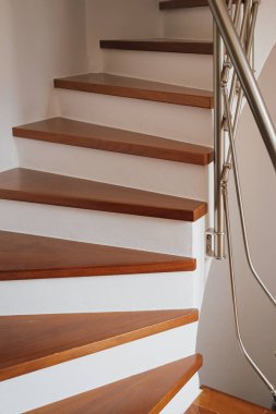 Beyaz duvarları, şık mimarisi ve rahat ev dekorasyonu olan kahverengi parke basamaklı sarmal merdiven..