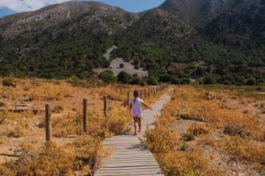 Girit dağlarında tahta patikada yürüyen küçük bir kız güneşli bir günde Yunan doğasını keşfediyor ve huzurlu bir açık hava manzarasının tadını çıkarıyor..