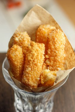 Kağıt ve bardakta lezzetli peynir çubukları.