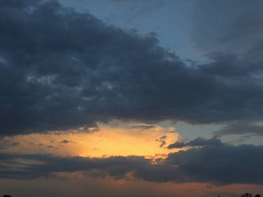 Alacakaranlıkta gökyüzü bulutlar ve solan güneşle kaplıdır. Sakin, doğadan esinlenilmiş bir manzara arka plan ya da mevsimsel konsept için mükemmel.