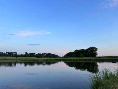 Akşamları huzurlu bir gölet bulutlu gökyüzünü yansıtır. Sakin bir su ve sakin bir atmosfer yakalar..