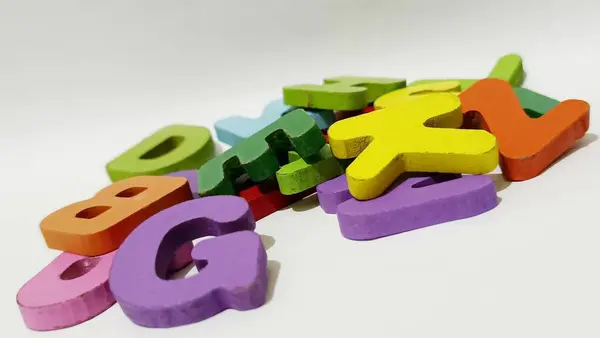 Beyaz arka planda ahşap harflerden yapılmış renkli harfler