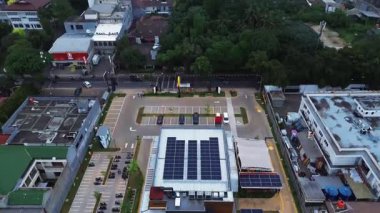 Çatıda güneş panelleri olan, otopark ve yerleşim yerleriyle çevrili bir binanın insansız hava aracı görüntüleri. DKI Jakarta, Endonezya - 30 Aralık 2024