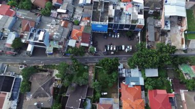 Yüksek açılı insansız hava aracı görüntüleri konut caddesi, evler, arabalar ve yemyeşil ağaçlar. İnşaat stilleri ve peyzaj karışımı bir şey gösteriyor. DKI Jakarta, Endonezya - 30 Aralık 2024