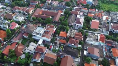 Yoğun yerleşim alanının yüksek açılı insansız hava aracı görüntüleri. Birçok ev, ağaç ve cadde var..