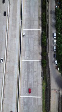 Otoyol trafiğinin yukarıdan görünüşü. Arabalar çok şeritli yolda gider. Park etmiş araçlarla yan yol.