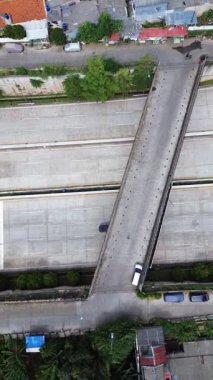 Üstten insansız hava araçları ile otoyol üst geçidi, arabalar şehir sokaklarını ve yeşillikleri gösteriyor..