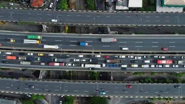 Otoyol trafiğinin yukarıdan aşağı görüntüsü, birden fazla şerit boyunca hareket eden çeşitli araçları gösteriyor. Arabalar, kamyonlar ve otobüsler. DKI Jakarta, Endonezya - 09 Januari 2025
