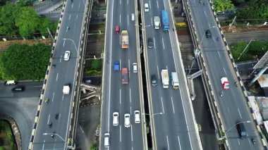Şehir manzarası ile çevrili, yoğun trafik akışına sahip, çok şeritli bir otoyolun yüksek açılı görüntüsü.