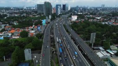 Yoğun bir şehir otoyolunun yüksek açılı görüntüsü. Çeşitli araçları ve çevre kentsel manzarası var. DKI Jakarta, Endonezya - 09 Januari 2025