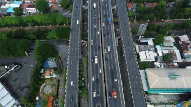 Şehir ve banliyö bölgeleriyle çevrili yoğun trafiği olan çok şeritli bir otoyolun yüksek açılı görüntüsü..