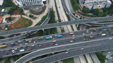 Yoğun bir otoyol kavşağının çeşitli araçlar ve çevre kentsel manzara ile yüksek açılı görüntüsü.