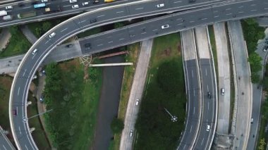 Yoğun trafik akışı olan yoğun bir otoyol kavşağının insansız hava aracı görüntüleri. Arabalar, kamyonlar ve motosikletler..
