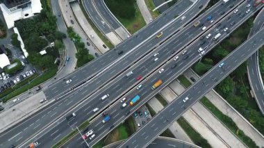 Yoğun bir otoyol kavşağının yüksek açılı görüntüsü çeşitli araçlar ve çevre yeşillik.