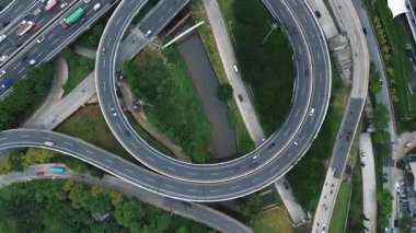 Arabalar ve kamyonlarla dolu bir otoyol kavşağının tepe noktası. Yeşiller yolların etrafını sarmış. DKI Jakarta, Endonezya - 10 Januari 2025