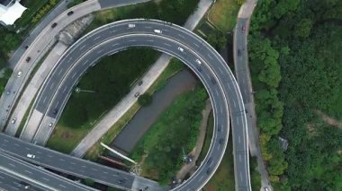 Yoğun trafik akışına sahip, yemyeşil bir otoban kavşağının insansız hava aracı görüntüleri..