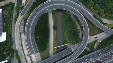 Yoğun bir otoyol kavşağının araçlar ve kamyonlarla çekilmiş robot görüntüleri. Yolları çevreleyen yemyeşil alanlar.