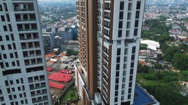 Geniş bir şehir manzarasına bakan tamamlanmış bir binanın yanında inşa halinde olan modern bir gökdelenin insansız hava aracı görüntüleri..