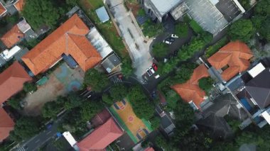 Okul binalarının, basketbol sahasının ve çevrenin insansız hava aracı görüntüleri. Kırmızı kiremit çatılar, yemyeşil ağaçlar..
