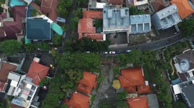 Şehirdeki evleri, yolları, arabaları ve kuş bakışı perspektiften yemyeşil ağaçları gösteren drone görüntüleri..