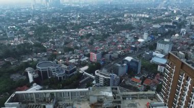 Şehrin yüksek açılı manzarası, konut alanları, binalar ve yolları gösteriyor. Yoğun şehir manzarası.