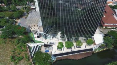 Çimenlik yeşillik ve otoparkla çevrili modern cam bir binanın robot görüntüleri. Şehir manzarası görünümü.