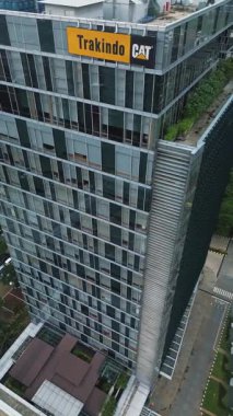 Şehir binaları ve otoparklarla çevrili Trakindo CAT tabelasıyla modern cam gökdelenin yüksek açılı görüntüsü. DKI Jakarta, Endonezya - 22 Ocak 2025