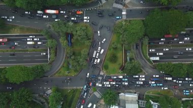 Yoğun trafik akışı ve çevre yeşillikle dolu bir şehir kavşağının insansız hava aracı görüntüleri..