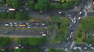 Yoğun trafik akışı ve çevre yeşillikle dolu bir şehir kavşağının insansız hava aracı görüntüleri..