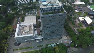 Yeşillik ve otoparklarla çevrili modern bir ofis kompleksinin insansız hava aracı görüntüleri. Şehir manzaralı. DKI Jakarta, Endonezya - 22 Ocak 2025