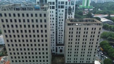 Üç şehir binasının yüksek açılı görüntüsü, biri modern ve ikisi daha eski, yollar ve yemyeşil ile çevrili. Yoğun trafik görünüyor. DKI Jakarta, Endonezya - 22 Ocak 2025