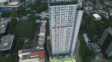 Evler ve yeşilliklerle çevrili uzun ve modern bir apartmanın yüksek açılı insansız hava aracı görüntüleri..