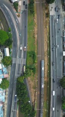 Yoğun yollar ve şehir manzarasının yanından geçen bir trenin yüksek açılı görüntüsü. Araçlar yollar boyunca hareket eder. DKI Jakarta, Endonezya - 25 Ocak 2025